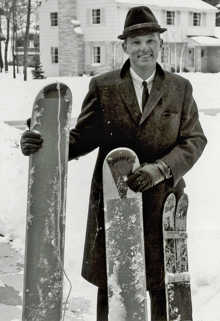 Poppen, standing outside in the snow, holding 3 Snurfer prototypes