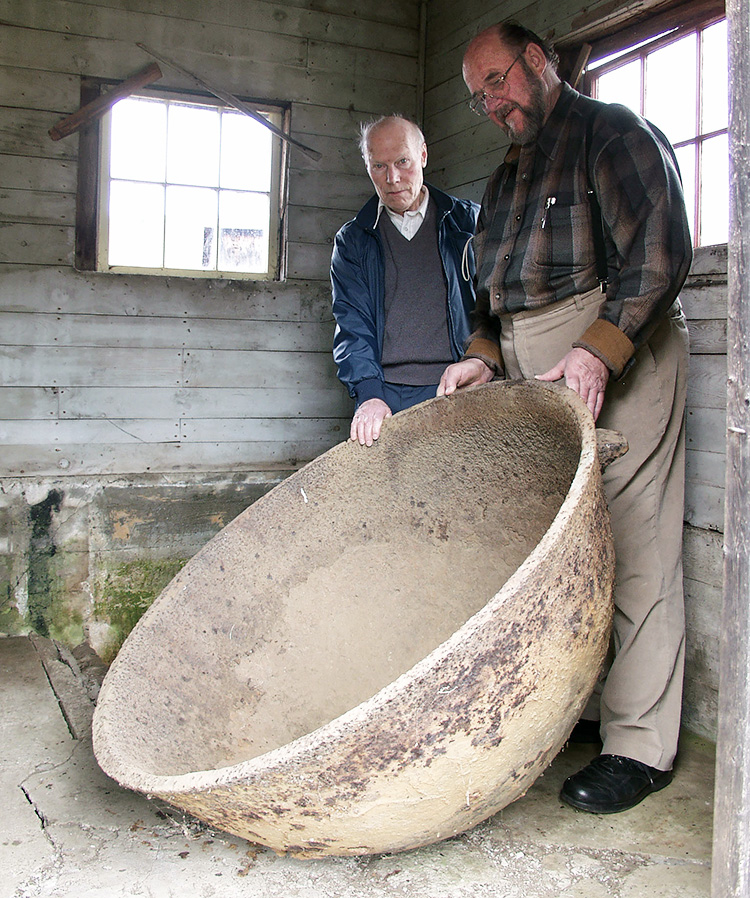 Two men standing, holding a large circular vessel