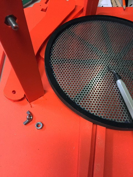 Perforated round disc on an orange metal support