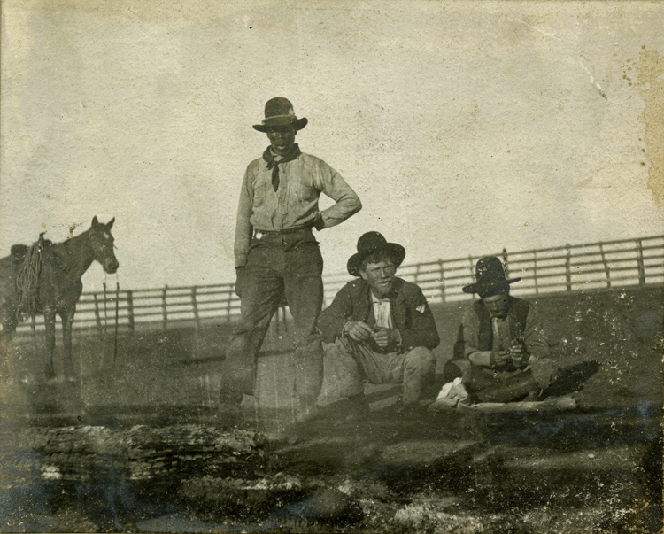 Three cowboys, including one African American cowboy, relaxing in Texas around 1900