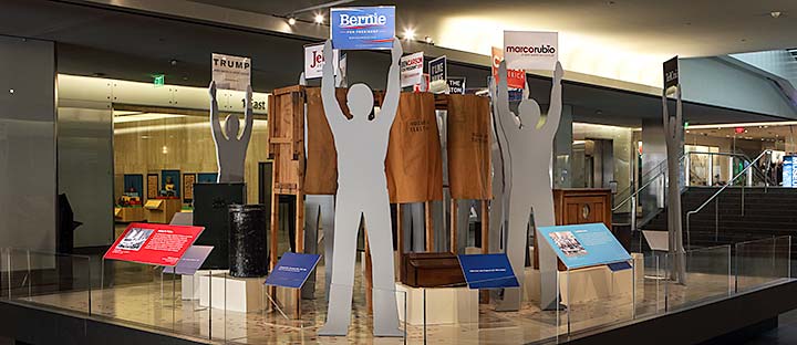 A display of historical voting apparatus and modern campaign posters at the National Museum of American History