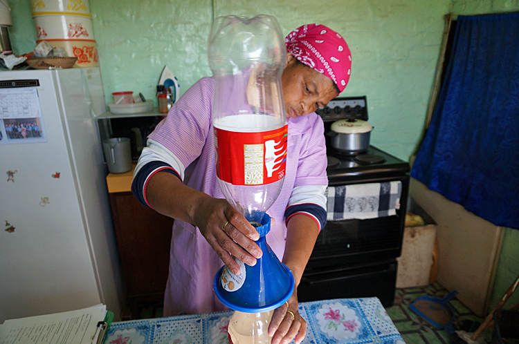 A woman in her kitchen in South Africa pouring water through Folia Water filter, 2016
