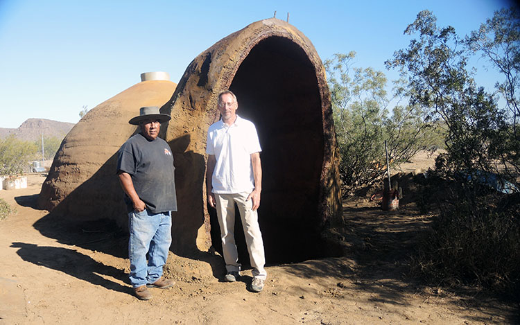 Two men standing outside a dome-shaped structure with an arched entrance