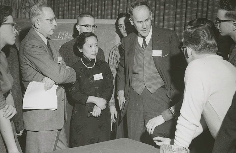 Chien-Shiung Wu standing in a group of 8 other people who are listening to a conversation between 2 of the men