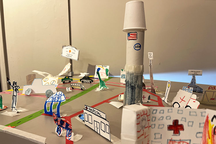 A town made of paper and craft materials, with a hospital, a NASA rocket, and other buildings