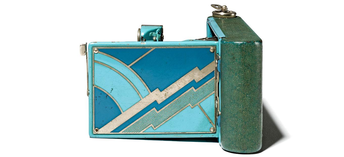 Back of a folding camera, with an Art Deco lightning pattern in shades of blue and aqua.