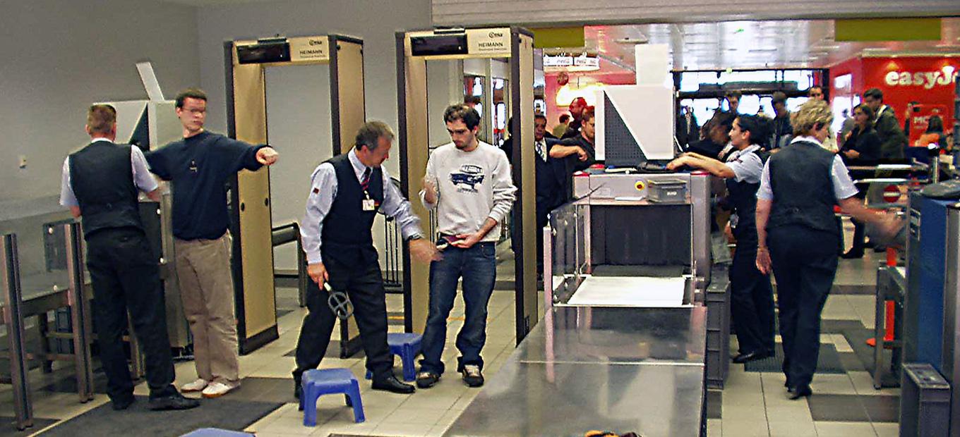 People passing through metal detectors and baggage x-ray at an airport