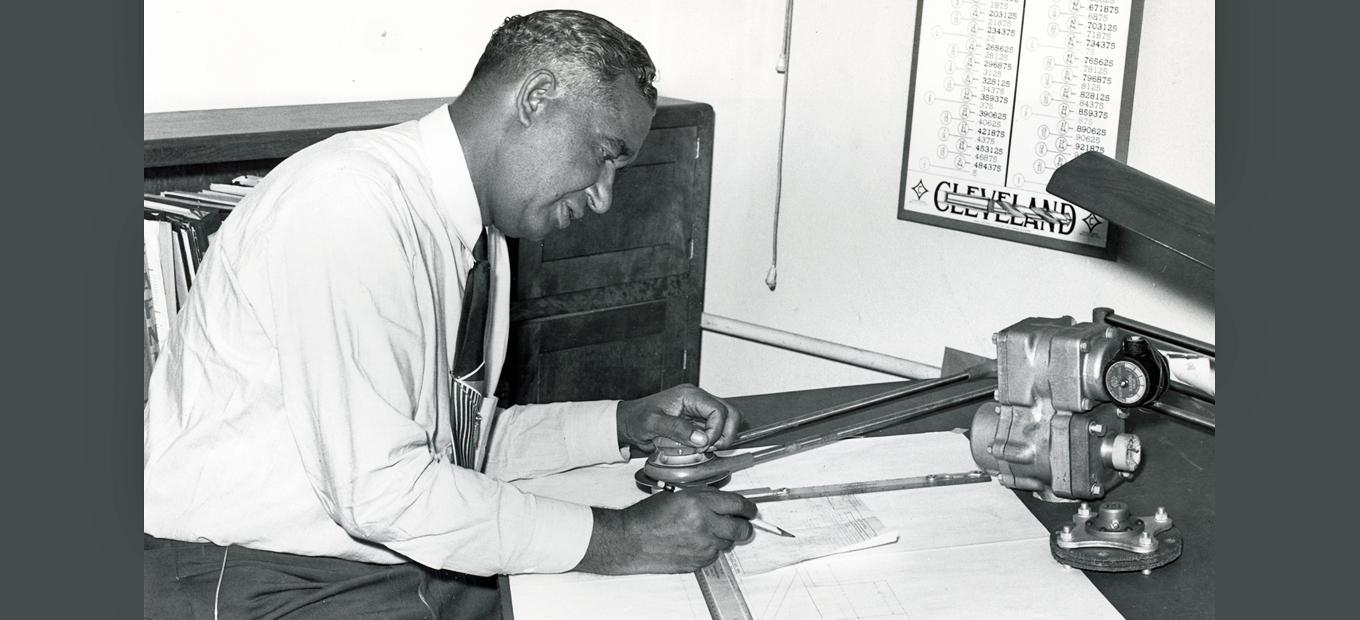 Frederick McKinley Jones working with a pencil and mechanical drawing at his drafting table, undated.