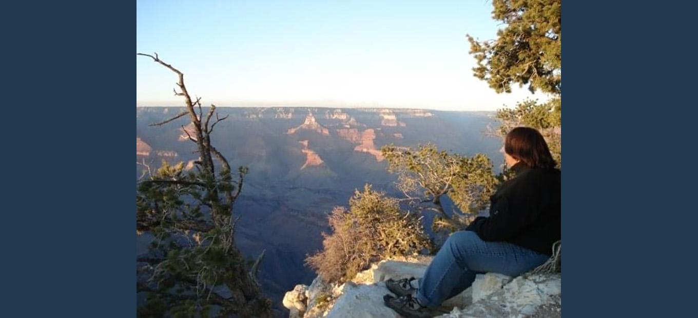 Kristen Sheldon sitting on the ground and looking across the Grand Canyon