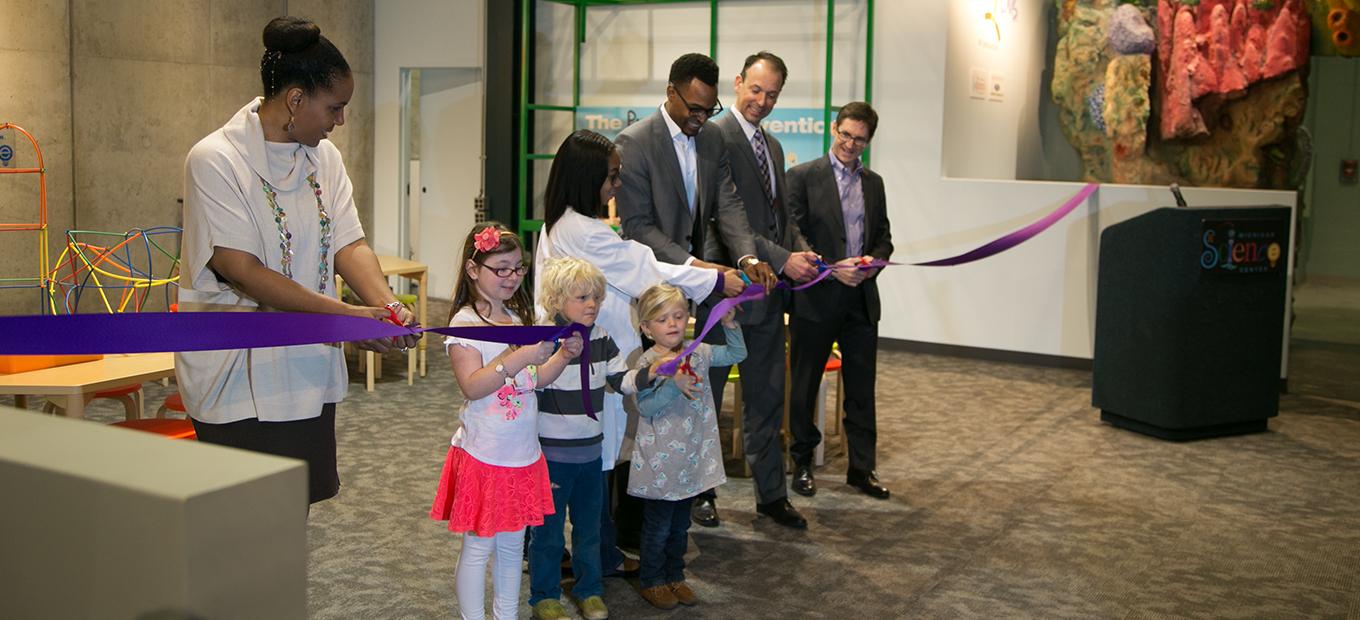 Smithsonian, Ford, and Michigan Science Center officials cut the ribbon to the newest Spark!Lab with the help of a few young visitors