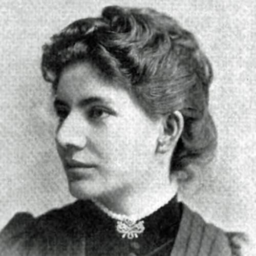 A three-quarters profile head-and-shoulders halftone of architect Sophia Hayden, 1892. She has her hair up in loose waves and wears a high-collared dress, with buttons to the neckline and V-shaped pleats from the shoulders, and a brooch at her throat.