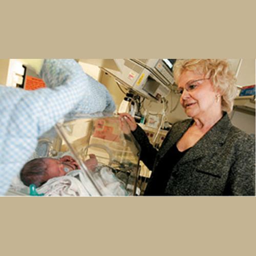 Inventor Sharon Rogone looking at a premature baby in a hospital bed