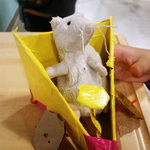 A toy mouse in a yellow, wedge-shaped car