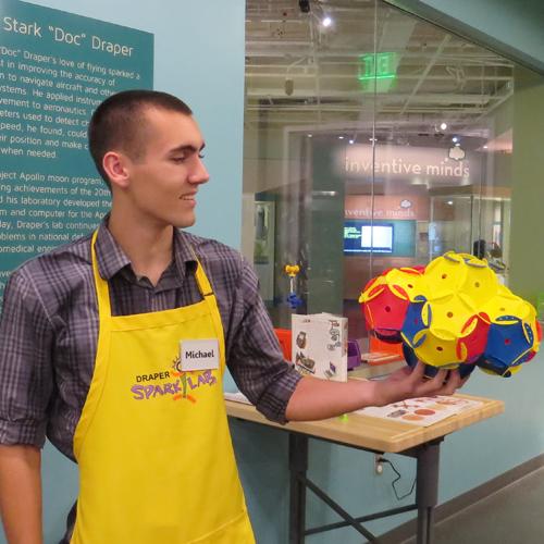 SparkLab volunteer in his yellow apron, holding completed activity