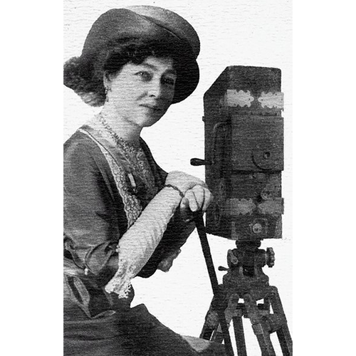 Black and white photo of Early French cinema pioneer Alice Guy-Blaché standing with camera tripod.